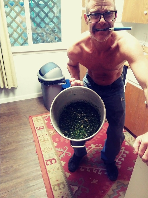 Todd Moon of Austin, Texas the Creator of Trail Relish holding a bucket of trail relish with a knife in his mouth